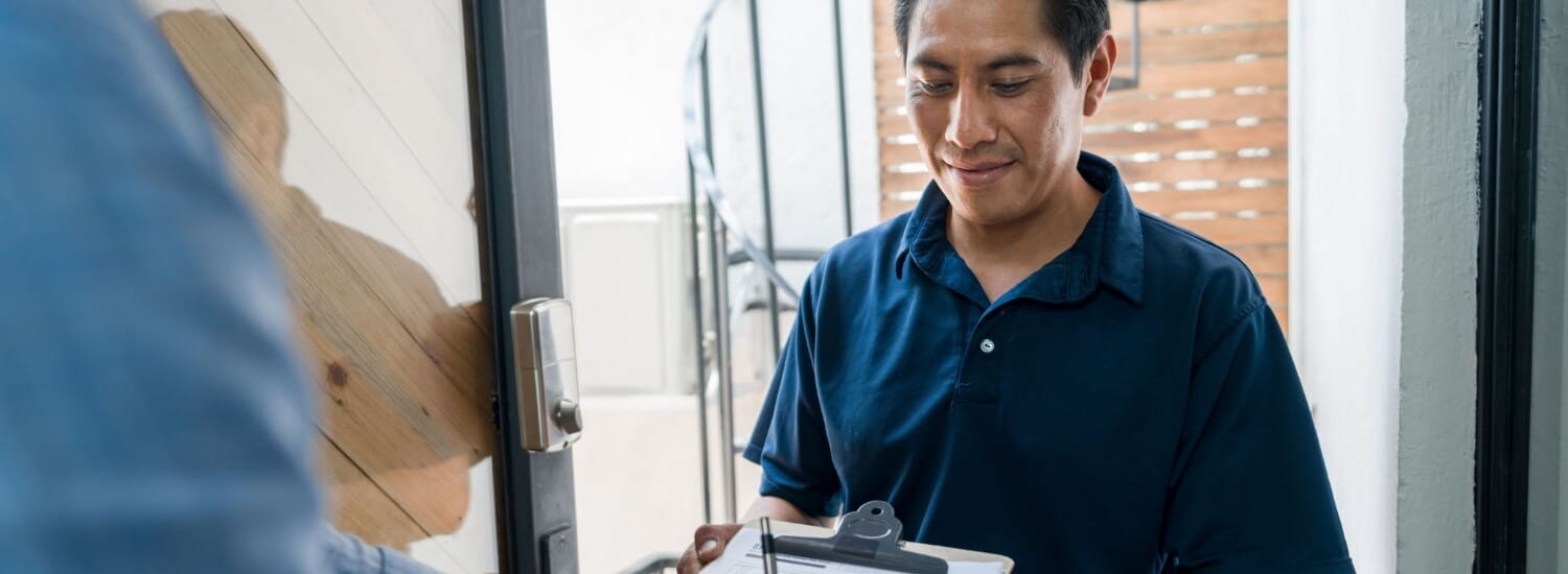 Man in blue shirt at front door with clipboard
